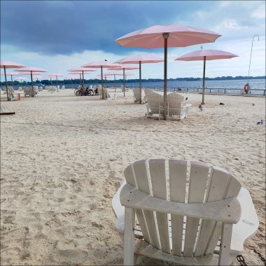 Sıcak bir yaz gününde şehirde pembe şemsiyeli bir sahil parkı.