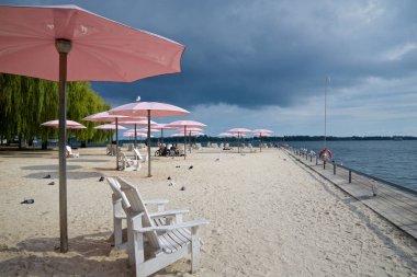 Şehir merkezindeki parktaki pembe plaj şemsiyeleri ve Adirondack sandalyeleri.