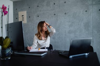 Orta yaşlı, kahverengi saçlı beyaz bir gazeteci şirkette yapılan bir toplantıdan bir rapor hazırlıyor. Ayrıca masasında bir sürü ışık ve çiçek olan hoş bir çevreyi de sever.. 