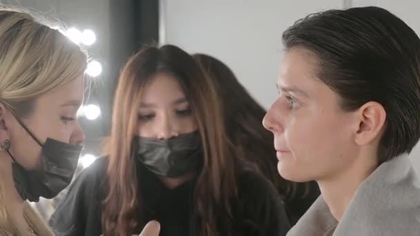 Escena entre bastidores: Las modelos hacen un maquillaje y un peinado antes de comenzar un desfile de moda. — Vídeo de stock