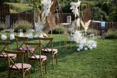 Çimenli yeşil bir çimenlikte düğün süsleri. Tahtadan yapılmış bir sürü sandalye