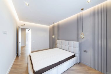Odanın iç tasarımı. Mavili büyük bir yatakla uyuyor.