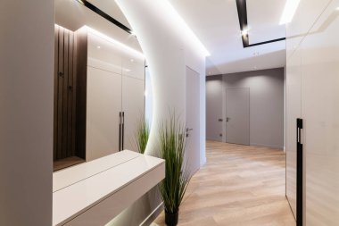 Koridorun içinde lambalar, aynalar ve bitkiler var.