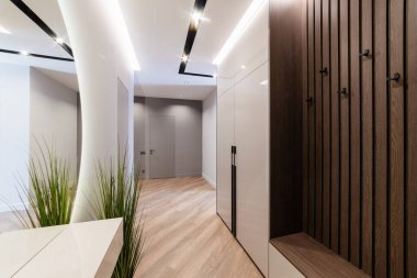 Evin içinde yeni bir koridor var. Aynası ve koyu renk ahşap duvarı var.