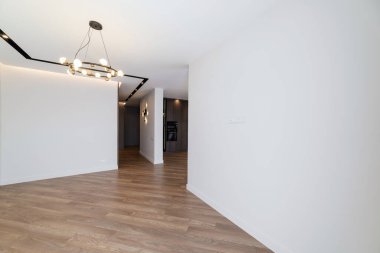 Beyaz duvarları ve doğal ahşaptan yapılmış zemini olan odanın içi.