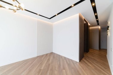 Beyaz duvarları ve koyu zemini olan yeni şık bir oda.