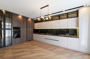 Beyaz bir mutfağın içinde, içinde lamba ve tavan arası aletleri olan bir evde.