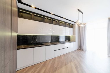 Odanın içinde büyük parlak pencereli yeni, temiz bir mutfak.