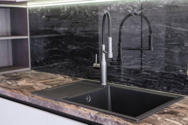 Yeni mutfak. Siyah lavabo ve metal musluk.