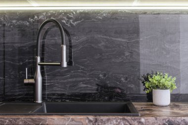 Yeni mutfak içi siyah lavabo ve metal muslukla dolu.