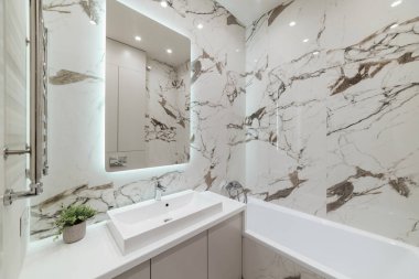 Beyaz küvetli ve aynalı parlak banyo iç tasarımı.