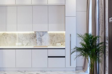 Arka aydınlatma dolapları ve dolabı olan yeni beyaz mutfak.