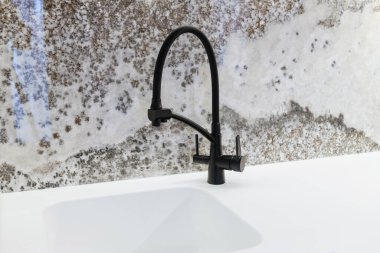 Mutfakta lavabo ve siyah metal musluk olan beyaz tezgah.