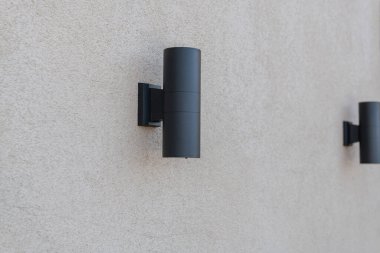 Duvarda siyah metal lambalar var.