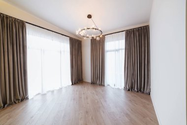 Evin içinde geniş pencereli büyük, parlak bir oda.