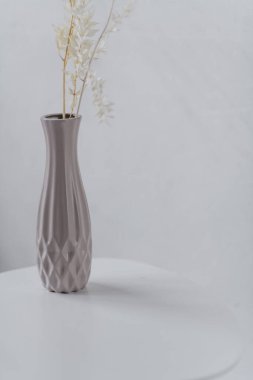 Beyaz arkaplanda dalları olan dekoratif vazo.