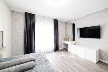 Geniş bir pencere ve televizyonla uyumak için büyük, şık bir tasarım odası.