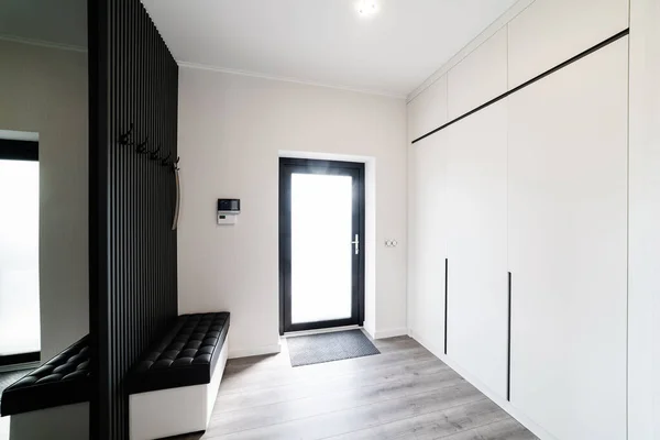 Modern interior design of the corridor in white. Bright wardrobe and black wood decor