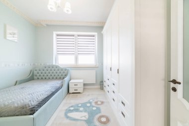 Pencere yatağı ve gardırobu olan çocuk odasının içi çok aydınlık.