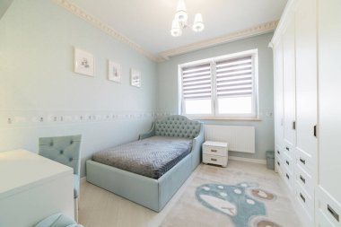 Geniş yataklı, kostümlü ve pencereli bir çocuk odası.