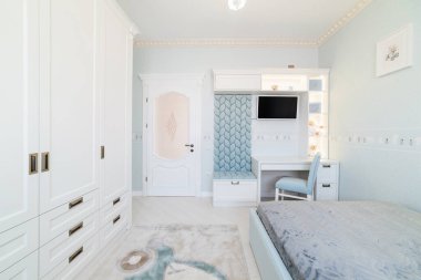 Açık renkli, gardırobu ve yatağı olan bir çocuk odasının iç tasarımı.