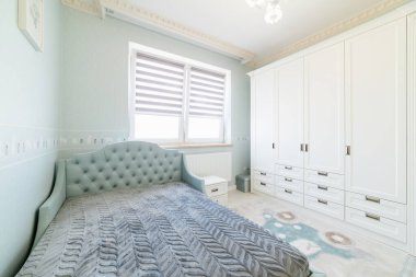 Beyaz gardırobu ve yatağı olan yeni parlak çocuk odası.