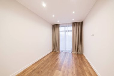 Yenilenmiş yeni bir evde beyaz bir oda. ahşap zemin ve geniş pencere