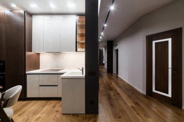 Geniş koridoru ve beyaz tezgahı olan mutfak stüdyosu.