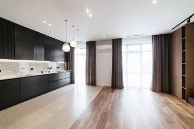 Karanlık mobilyaları ve geniş pencereleri olan mutfak stüdyosunun modern iç mekanı.