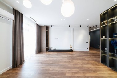 Geniş pencereli ve ahşap döşemeli modern evin içinde büyük bir oda.