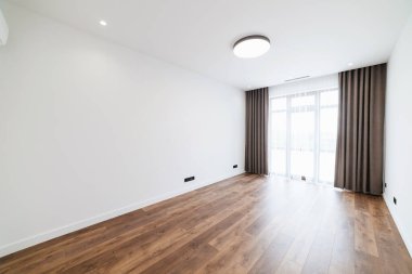 Geniş, büyük, boş bir oda, geniş bir pencere ve ahşap zemin.