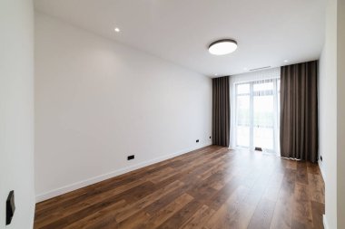 Beyaz duvarları ve ahşap zeminleri olan modern mazot bir oda.