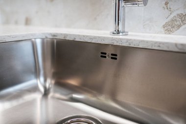 Modern bir iç tasarımla mutfakta gümüş bir lavabo var.