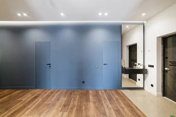 Mavi duvarı ve ahşap zemini olan yeni, şık, modern bir apartman tasarımı.