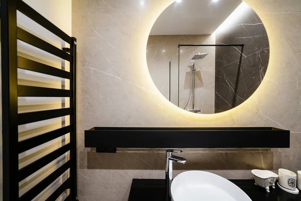 Large, round mirror with illumination in the bathroom. Loft Style