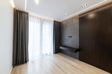 Evin yeni iç kısmında, ahşap bir duvarda geniş pencereli siyah perdeler.