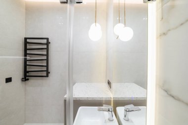 Parlak bir banyonun modern iç kısmında büyük bir ayna ve ışık.