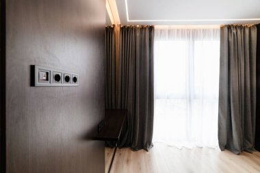 Büyük pencereli ve perdeli karanlık bir duvarı olan yeni bir oda.