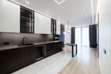 Büyük mutfak stüdyosu karanlık, hafif mobilyaları ve masası var.