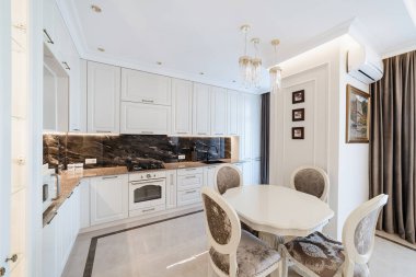 Beyaz mobilyalı ve masalı mutfak alanı