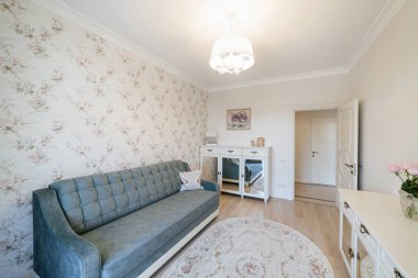 Odanın modern iç tasarımı, mavi kanepesi ve hafif mobilyası var.