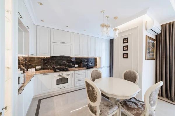 Beyaz mobilyalı ve masalı mutfak alanı