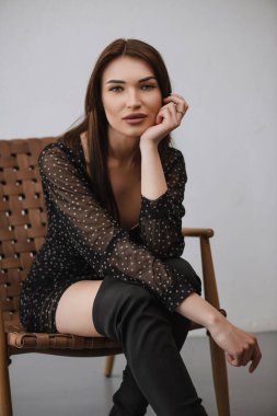 young girl posing on a chair in dark clothes