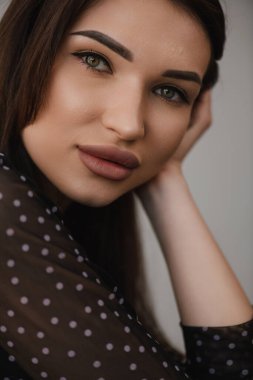 Beyaz arka planda siyah elbiseli, gülümseyen genç kız.