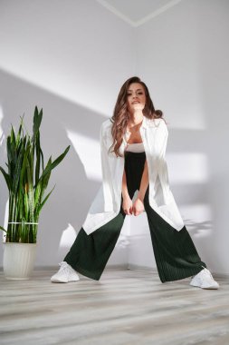 Beyaz bir duvarda genç ve güzel bir kızın fotoğrafı çekiliyor.