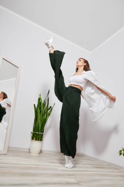 Şık elbiseli kız evde esneme hareketleri yapıyor.