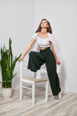 young beautiful girl in stylish clothes stands on a chair