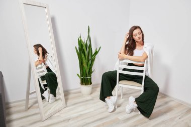 Stüdyoda beyaz tahta bir sandalyede oturan güzel bir kız.