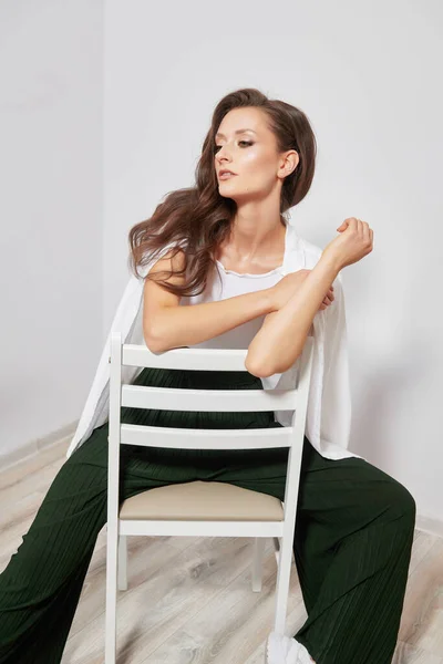 Beyaz Tahta Bir Sandalyede Poz Veren Şık Elbiseli Güzel Bir — Stok fotoğraf