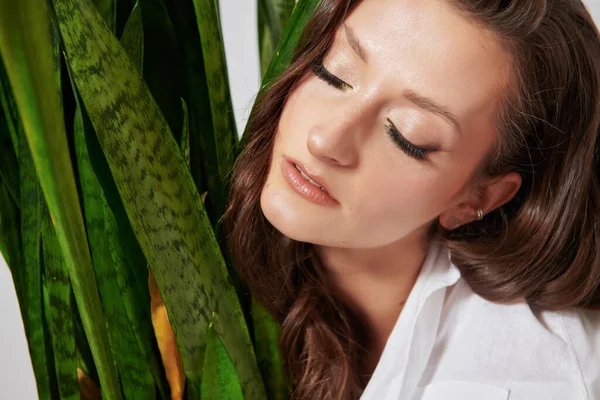 portrait of a girl with closed eyes with a green plant